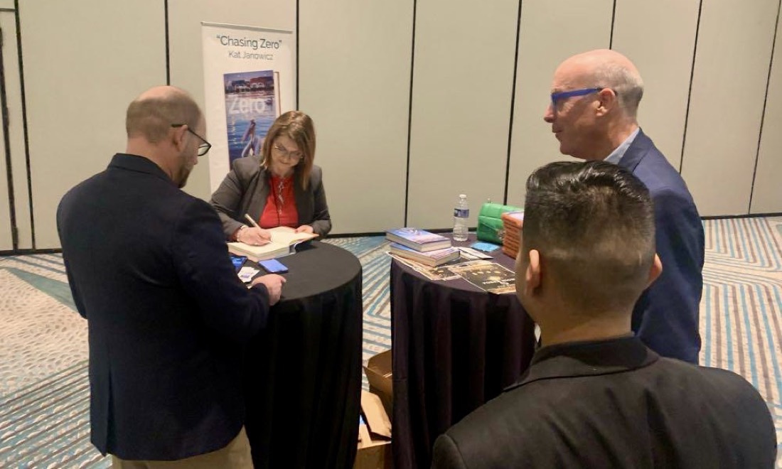 Kat Janowicz signing copies of Chasing Zero at an event, with readers waiting