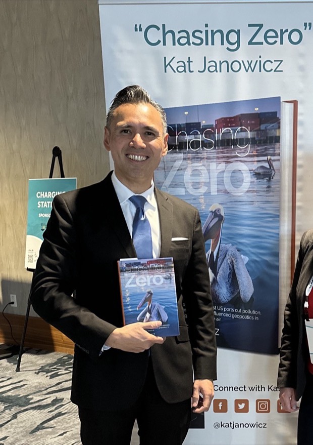 Noel Hacegaba holding Chasing Zero beside the book banner